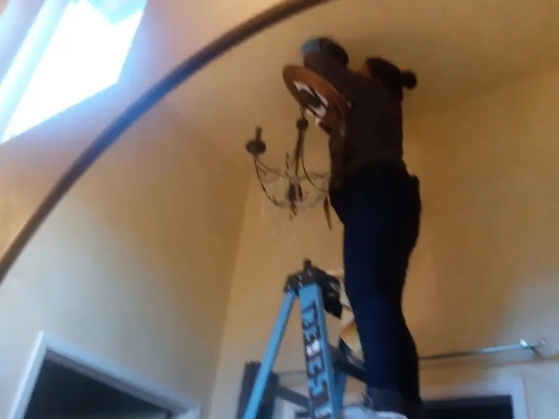 Electrician installing a chandelier in a Petal residence